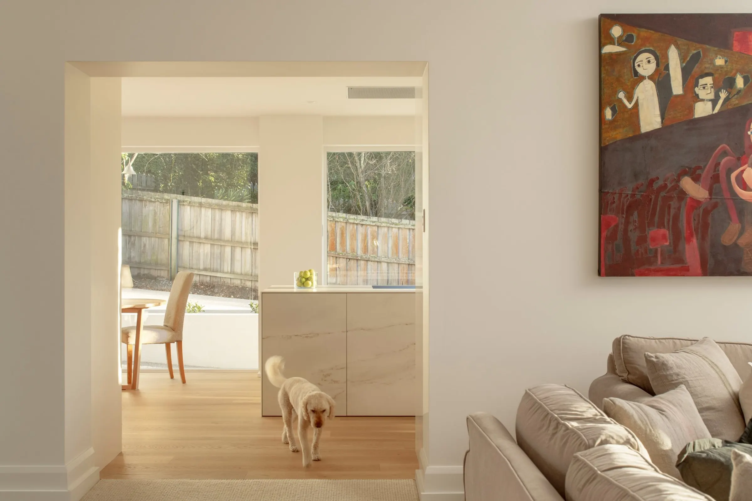 View from the living room through to the finished kitchen and dining, a dog crossing the oak floor, Newstead