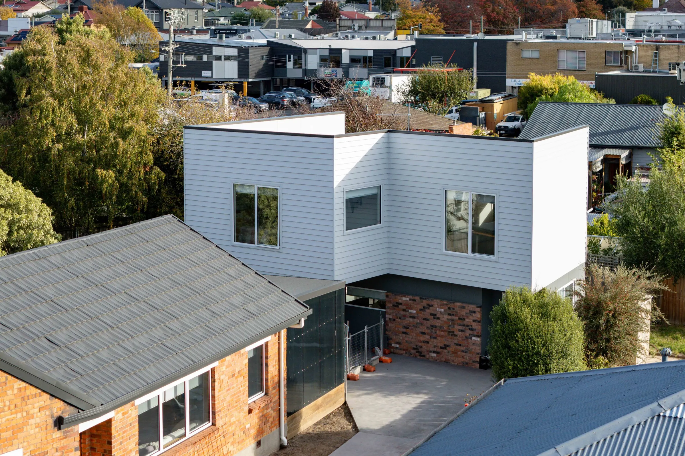 A finished two-storey weatherboard home with a brick lower level, seen from above, Newstead
